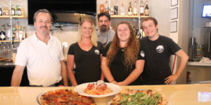 Ava's Pizzeria & Wine Bar Cambridge Employee's posing with their food highlighting their opening.